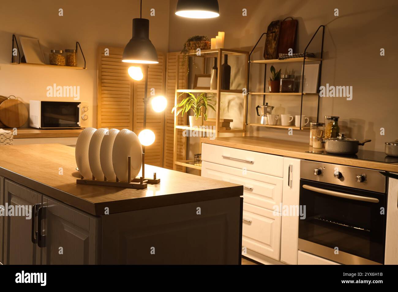 Interior of kitchen with counters, shelves and glowing lamps in evening ...