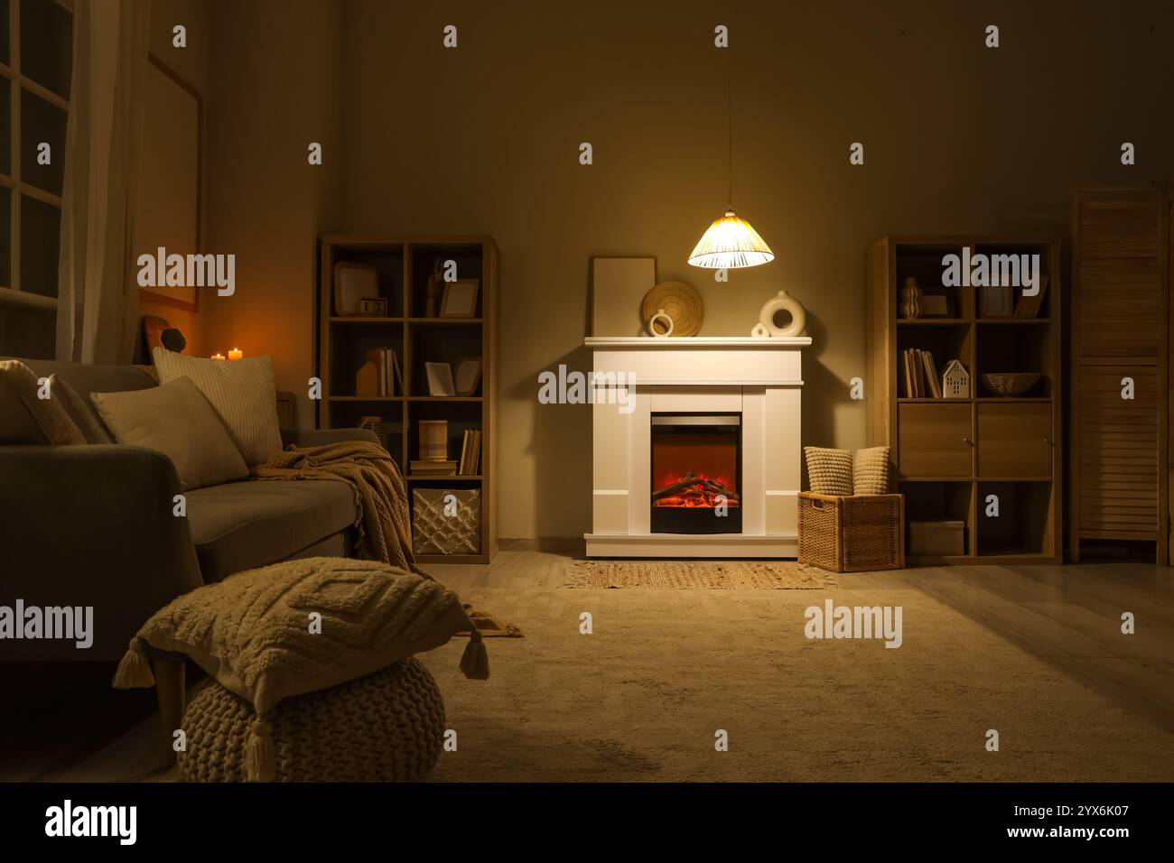 Interior of dark living room with fireplace, sofa and glowing lamp at ...