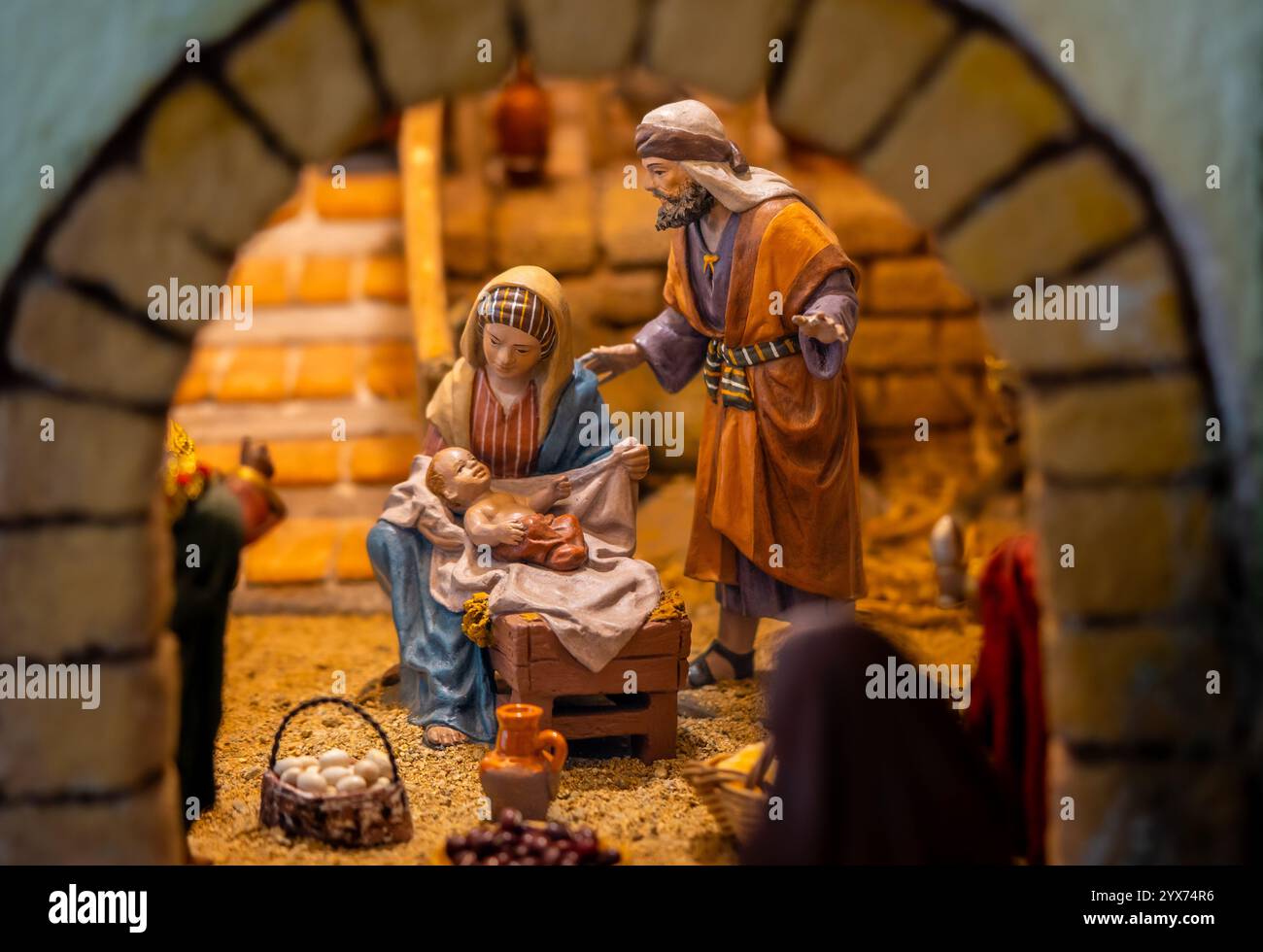Nativity scene with figures of Mary, Joseph and baby Jesus in a rustic manger with baskets of ...