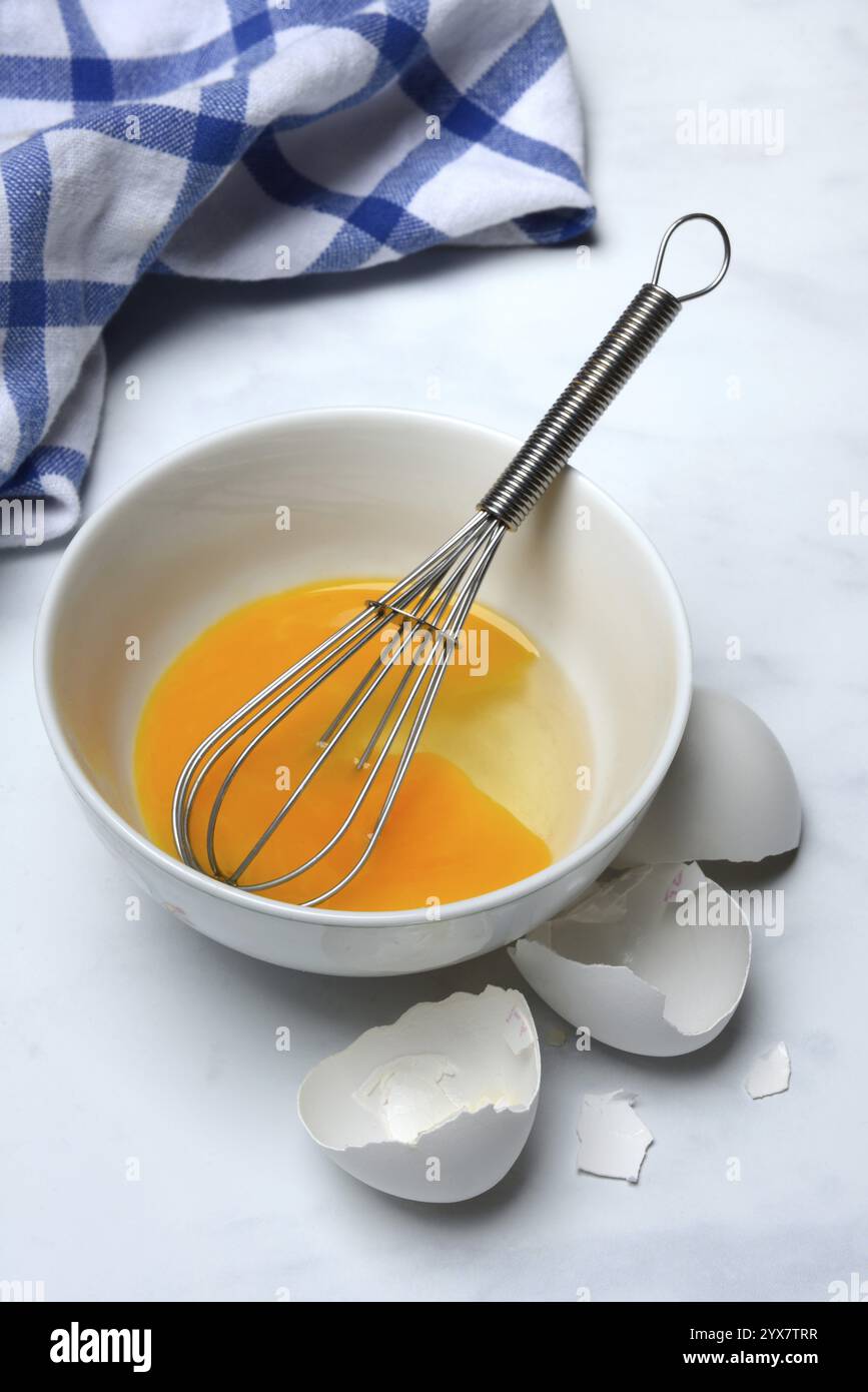 Whipped egg in shell with whisk, egg shells Stock Photo