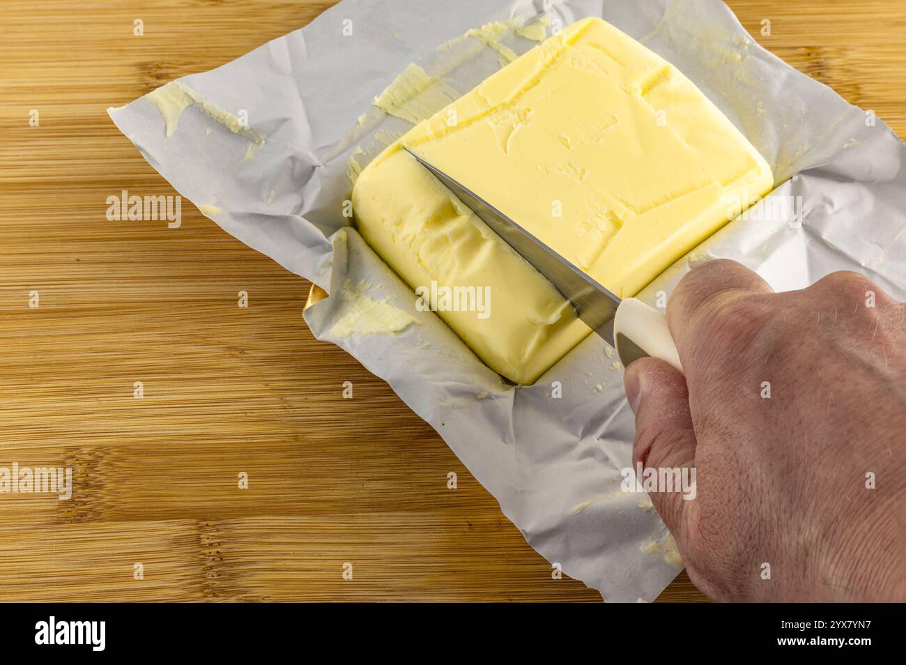 A stick of fresh butter on a wooden cutting board, a banknote, an increase in food prices Stock Photo