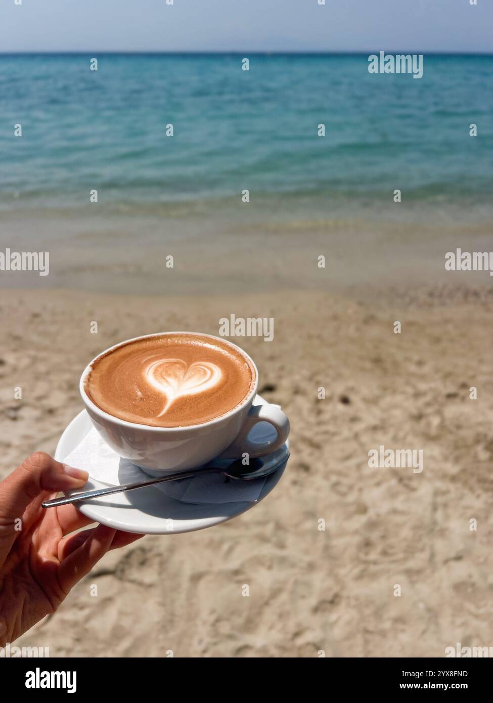 cup of coffee cappuccino on the beach front of the sea - Smartphone Captured Stock Image