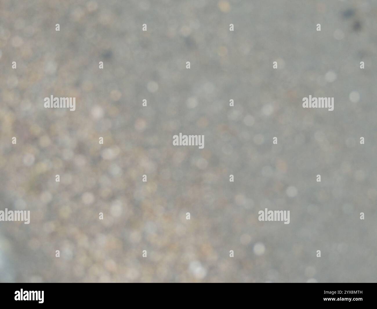 blurred river sand bank with brown and grey small pebbles as empty kopi space, grainy light natural texture in blur, bokeh of rocky shore Stock Photo