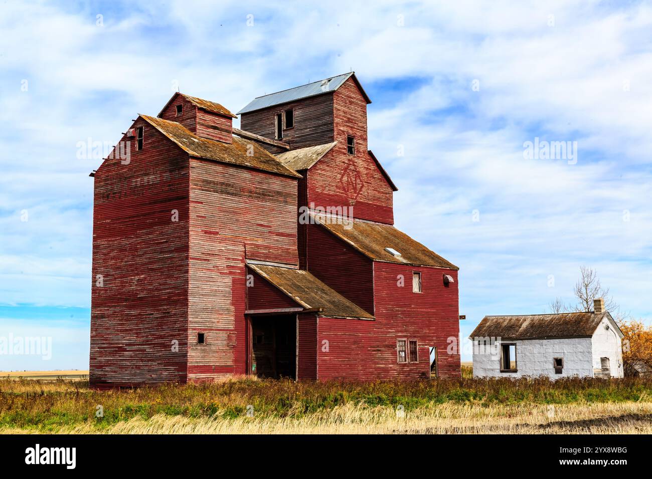 A red barn with a white house in the background. The barn is old and ...