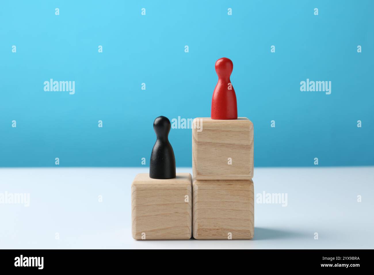 Human figures on stacked wooden blocks, red one on top against light ...