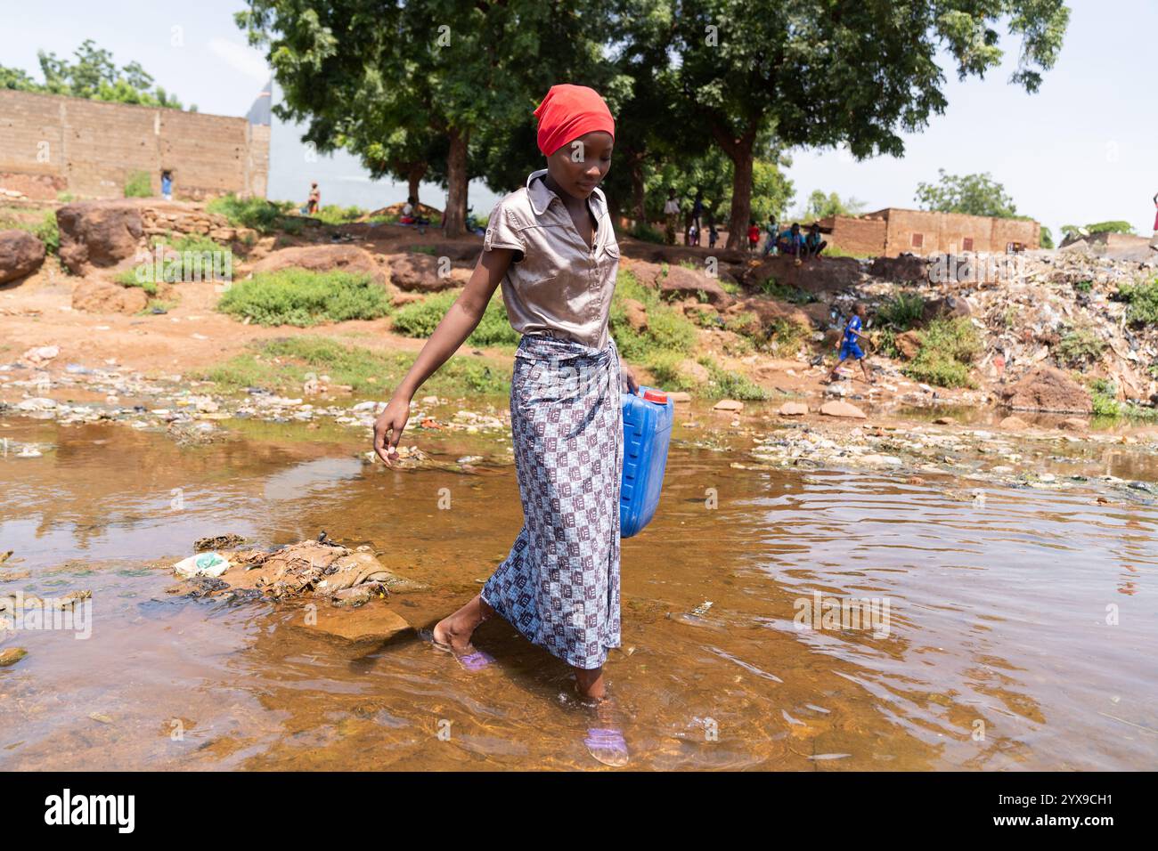 Young African girl crossing a flooded road after heavy rains; concept of climate change in third world countries Stock Photo