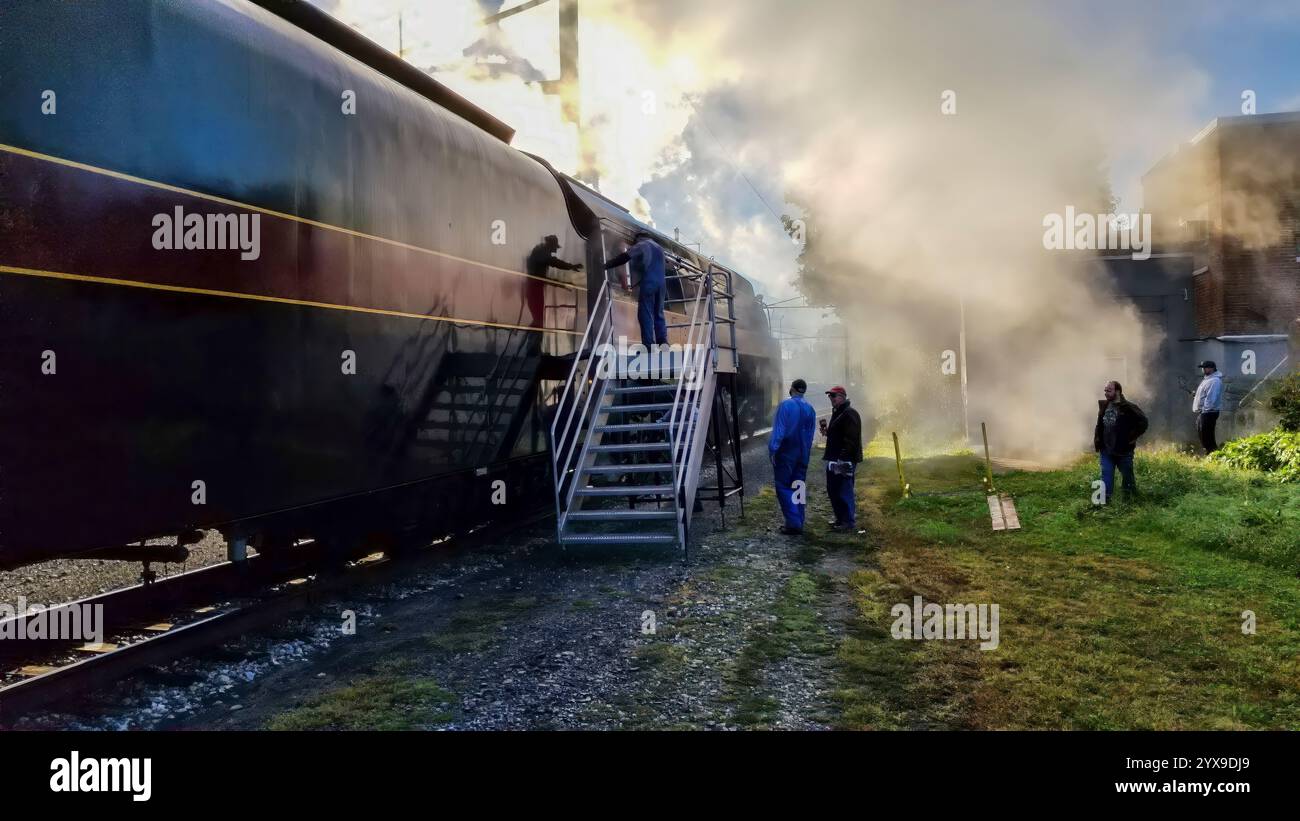 Workers in blue uniforms gather around a vintage train, tending to ...
