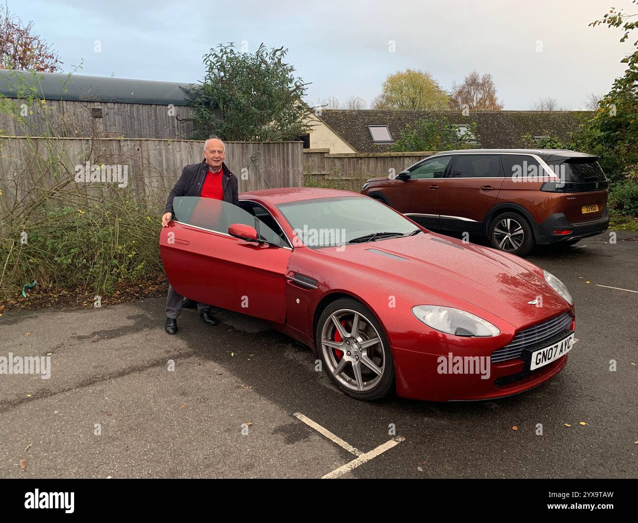 Aston Martin red colour coloured sports car fast British England James Bond sporty pose new car English 007 Bond James Cotswolds country man - Smartphone Captured Stock Image