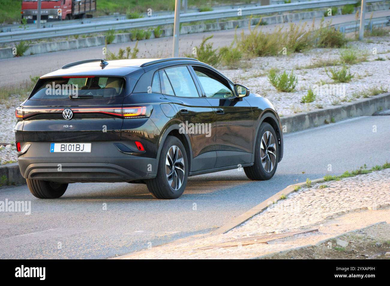 Modern electric volkswagen id.4 cruising on an asphalt road near a highway Stock Photo