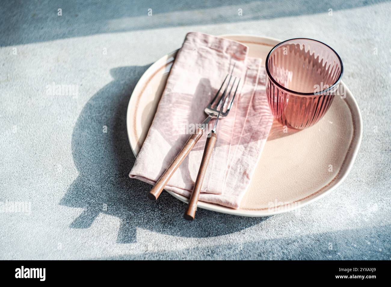 Close-up of a simple pink place setting on a table in sunlight Stock Photo
