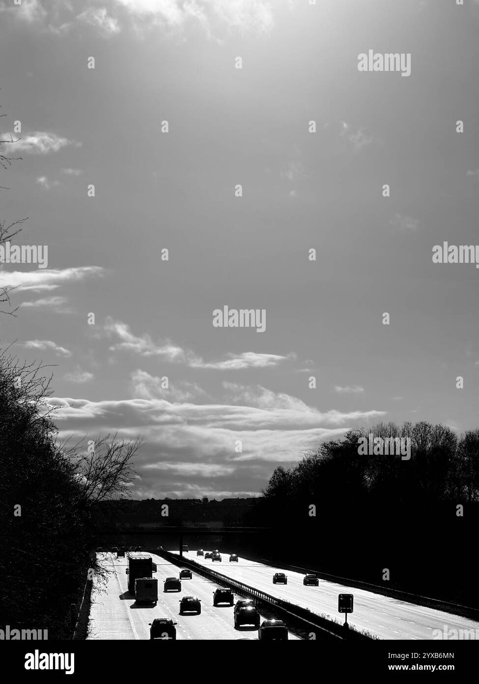 Aerial view from bridge looking into the sun of the M61 motorway at Adlington near Chorley in Lancashire with vehicles silhouetted against the light. - Smartphone Captured Stock Image