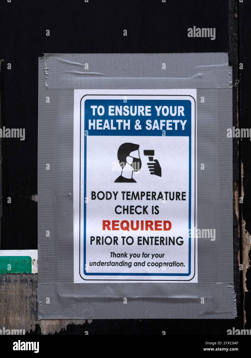 LONDON, UK - OCTOBER 22, 2021:  Old sign advising body temperature check required as part of Covid pandemic measures Stock Photo