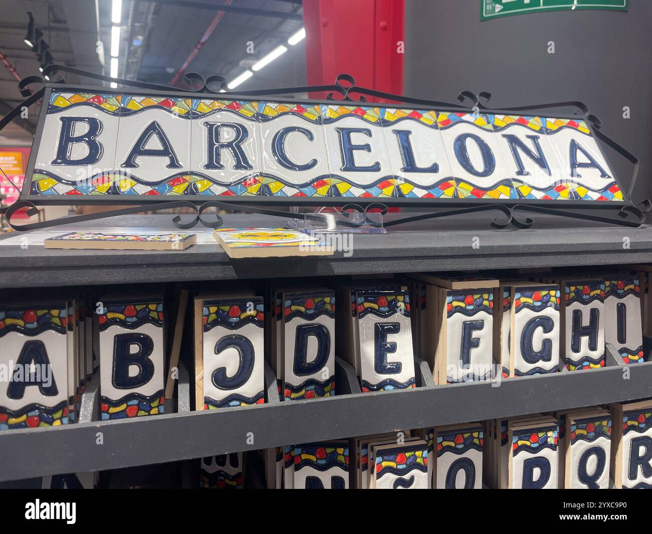 Ceramic tiles spelling 'Barcelona' with colorful patterns, displayed above individual letter tiles arranged below, Barcelona Airport, Catalonia, Spain - Smartphone Captured Stock Image