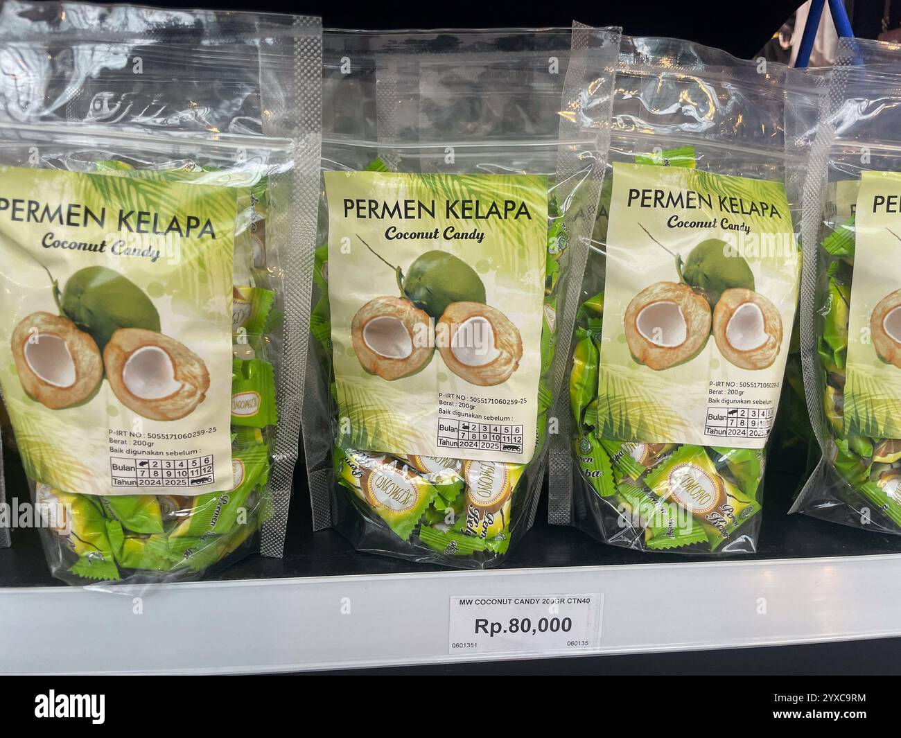 Bags of 'Permen Kelapa' coconut candy with green packaging, labeled 200g, and priced at Rp. 80,000, , Jakarta Airport, Indonesia - Smartphone Captured Stock Image