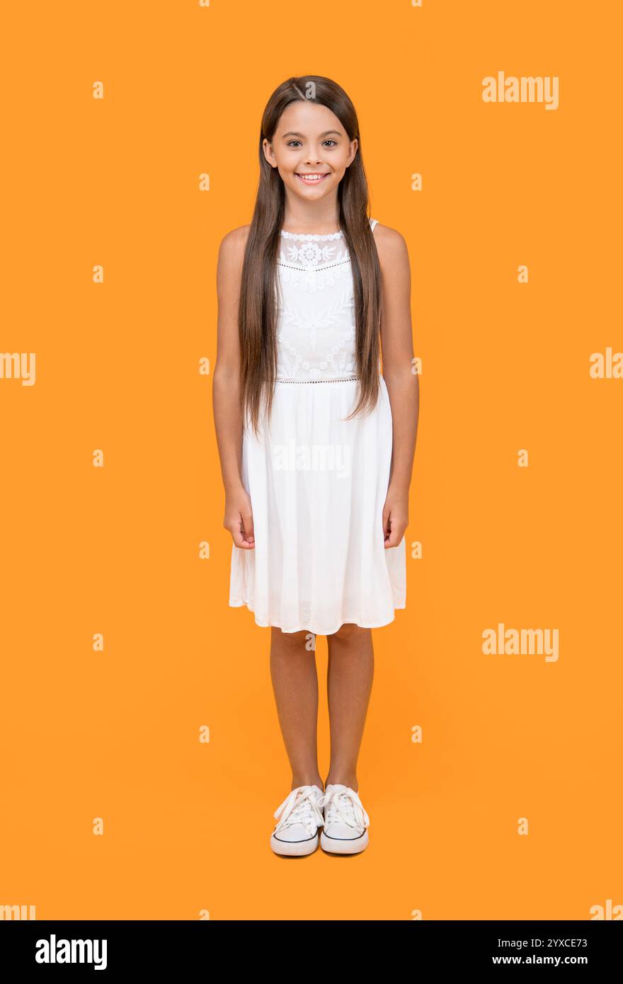 cute teen girl in white dress standing on yellow background Stock Photo ...