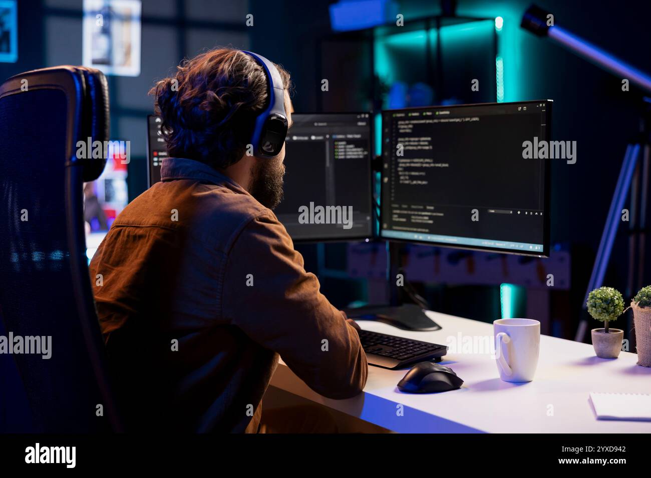 Man listening music while doing software quality assurance, reading source code on computer screen. Developer wearing headphones enjoying podcasts and inspecting coding on desktop PC Stock Photo