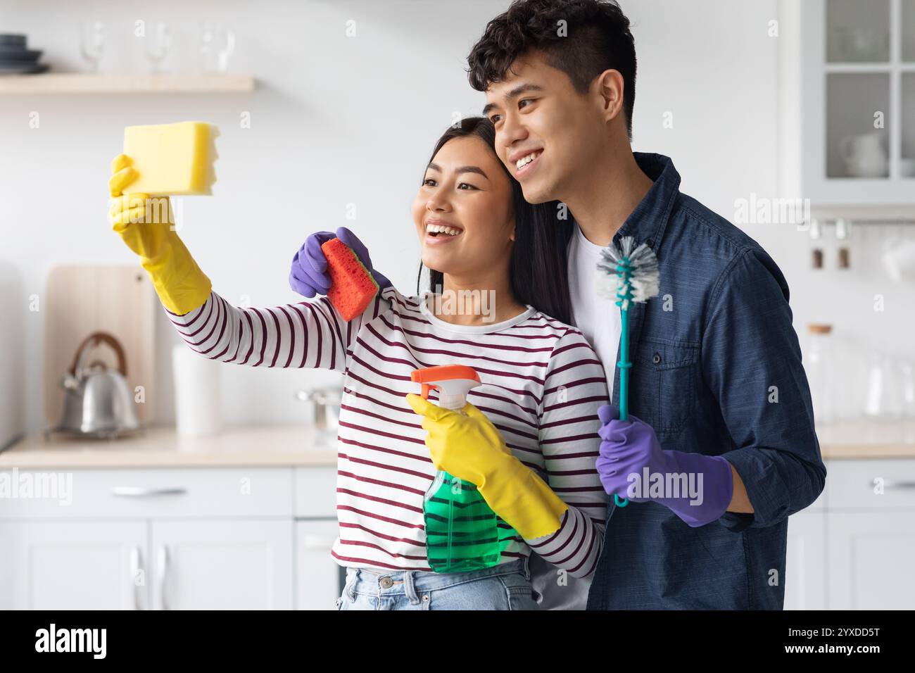 Cute asian couple taking selfie with sponge while cleaning kitchen Stock Photo