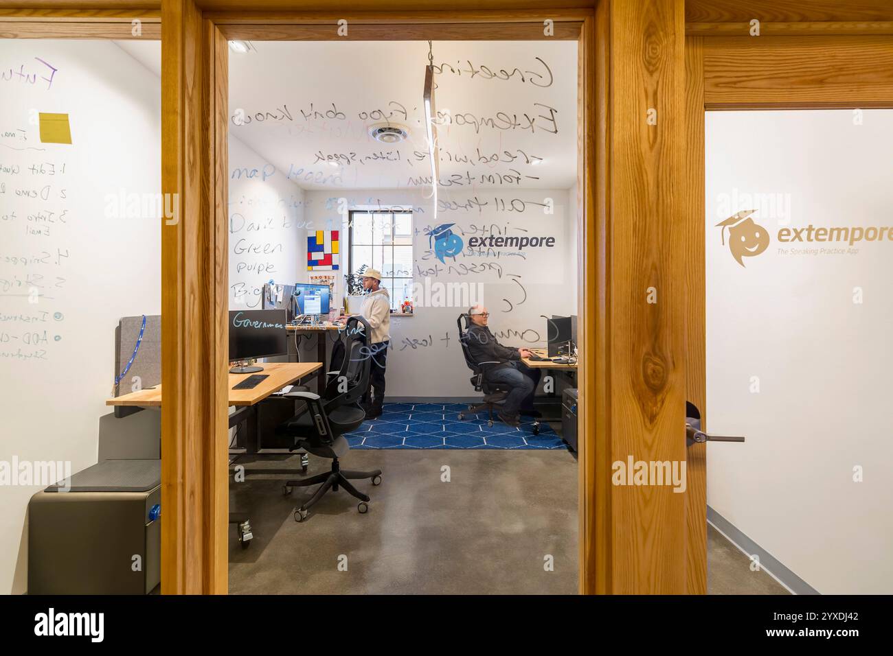 Two men working in office space behind glass door and windows Stock ...