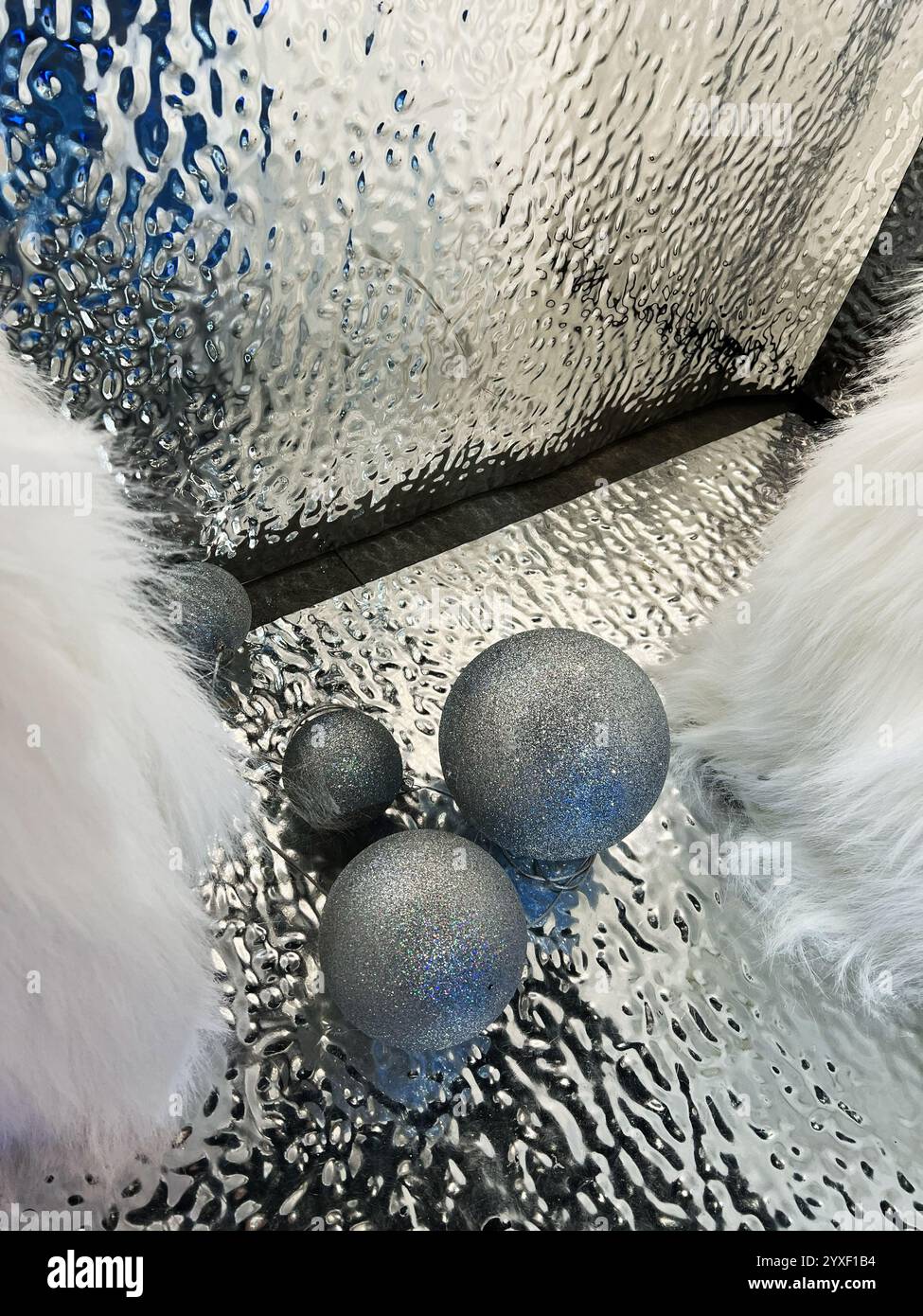 Shimmering silver spheres rest on a liquid-like reflective background ...