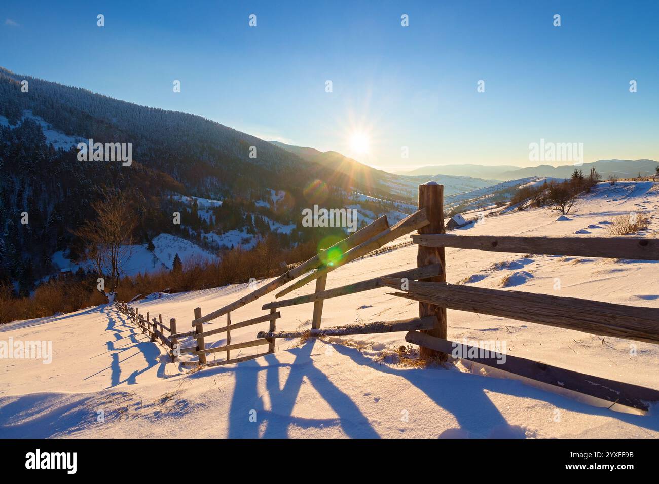 wooden fence on snow covered hill. mountainous carpathian countryside in winter Stock Photo