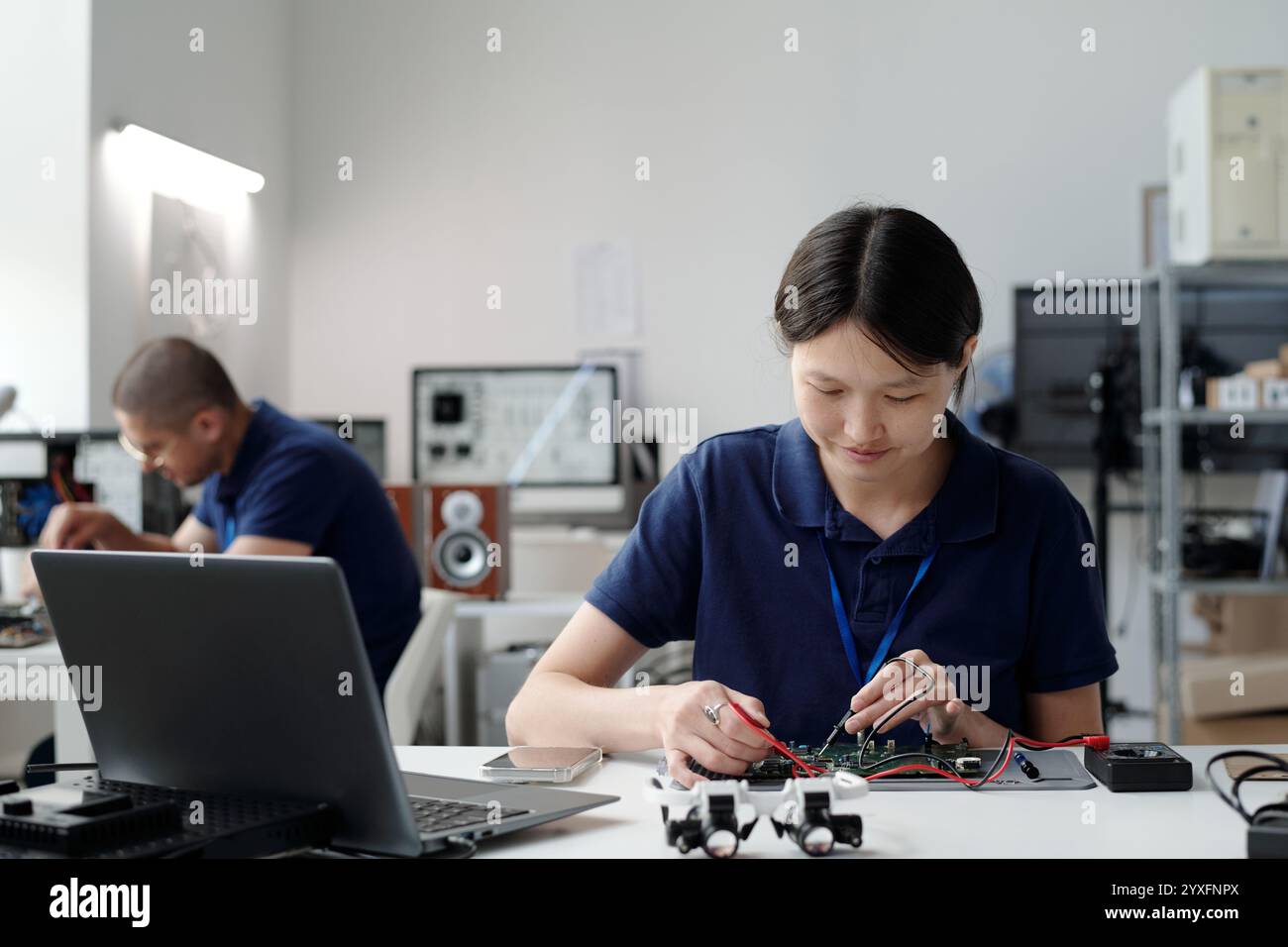 Asian Engineer Working on Electronic Device in Modern Lab Stock Photo