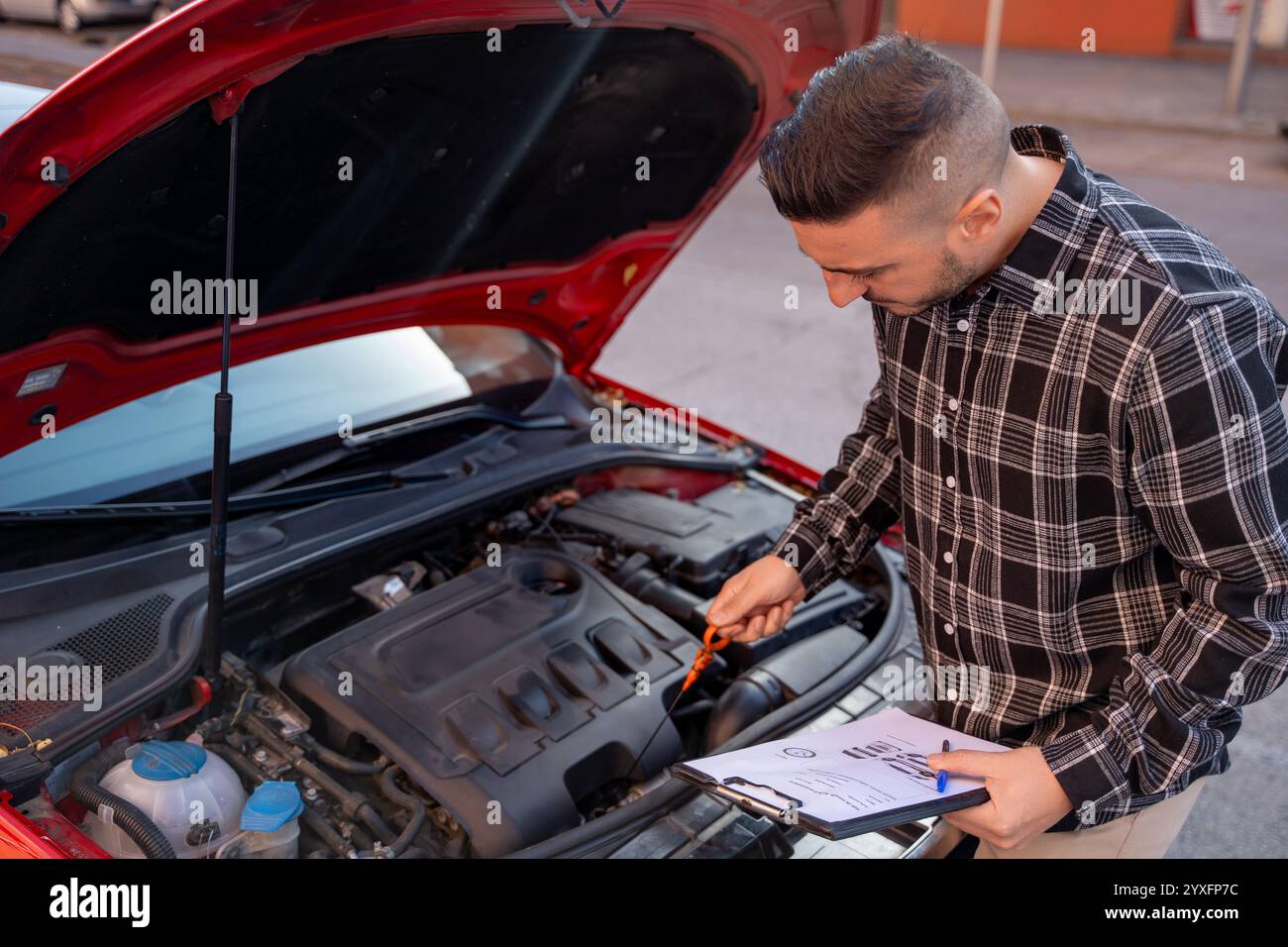Insurance agent inspecting a car engine and completing paperwork after ...