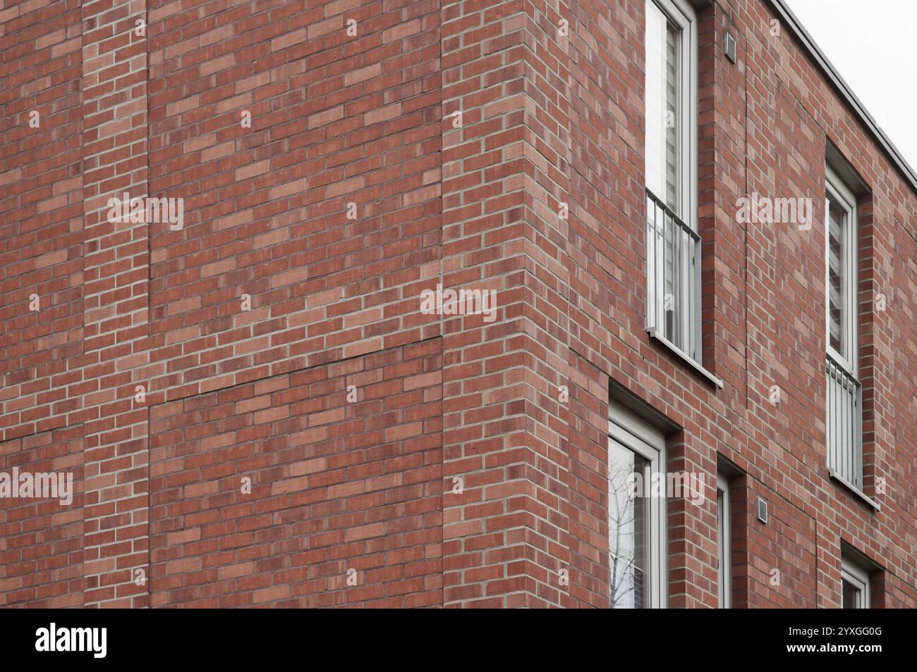 Red brick wall of a modern residential building with white windows and ...