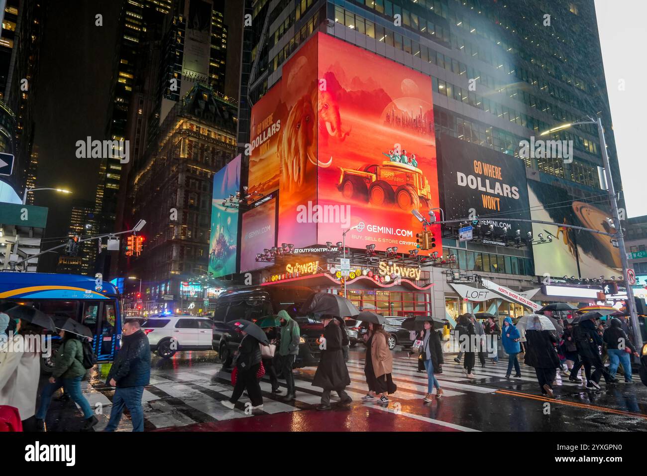 Crowds of people pass under an advertisement for the Winklevoss brothers' Gemini Cryptocurrency Exchange in the rain in Times Square in New York on Wednesday, December 11, 2024. Twins Cameron and Tyler Winklevoss founded the exchange in 2014 trading Bitcoin and other cryptocurrencies.  (© Richard B. Levine) Stock Photo