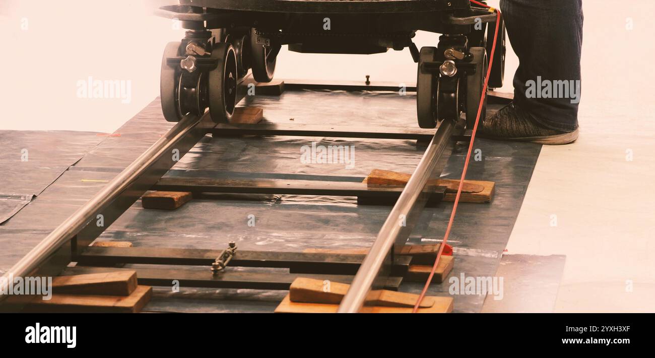 Camera trolley or camera dolly cart rails for filmmaking on studio shooting set. Pro videographer dolly rail track for filming movie mounted on studio Stock Photo