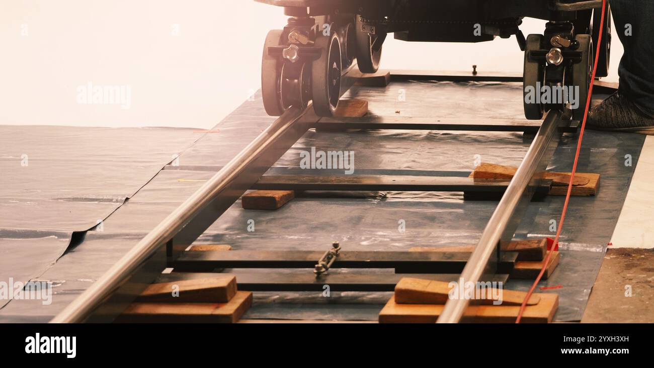 Camera trolley or camera dolly cart rails for filmmaking on studio shooting set. Pro videographer dolly rail track for filming movie mounted on studio Stock Photo