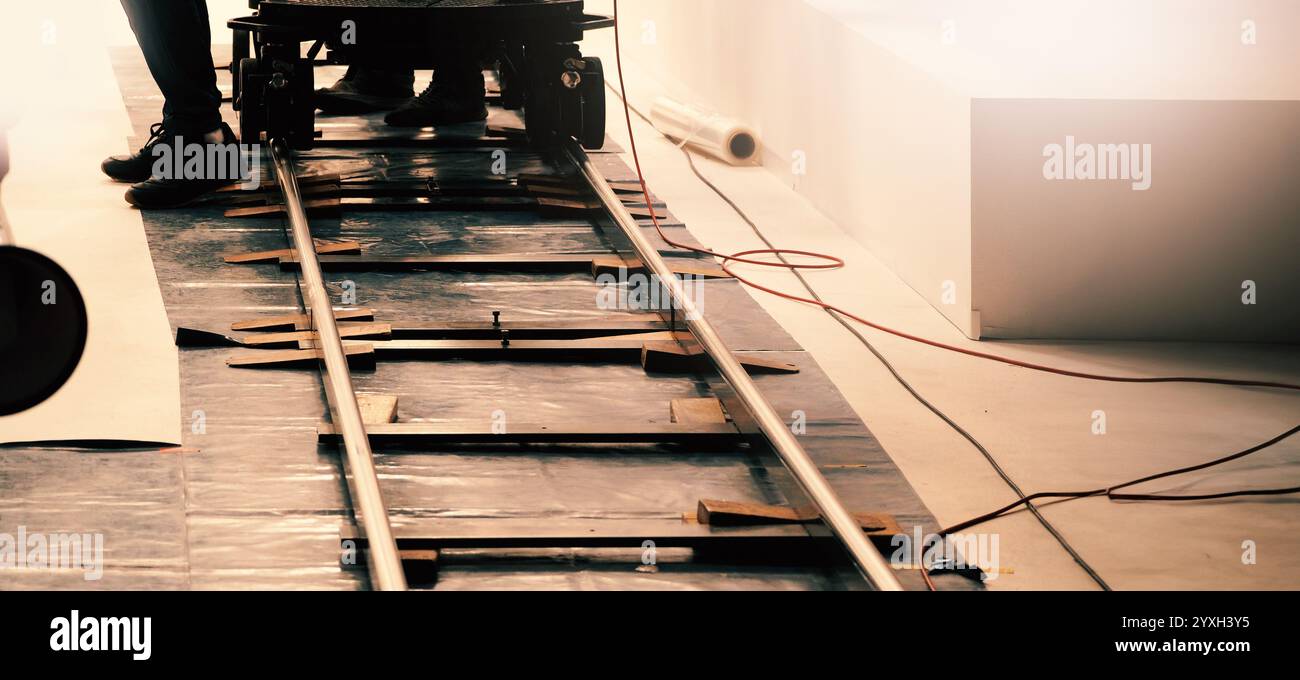 Camera trolley or camera dolly cart rails for filmmaking on studio shooting set. Pro videographer dolly rail track for filming movie mounted on studio Stock Photo