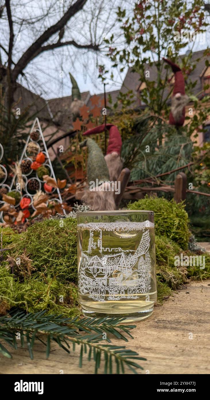 'Ambiance féerique au marché de Noël de Kaysersberg : un verre gravé de vin chaud posé sur un lit de mousse, entouré de décorations naturelles et de charmants lutins veillant sur l'esprit des fêtes.' - Smartphone Captured Stock Image