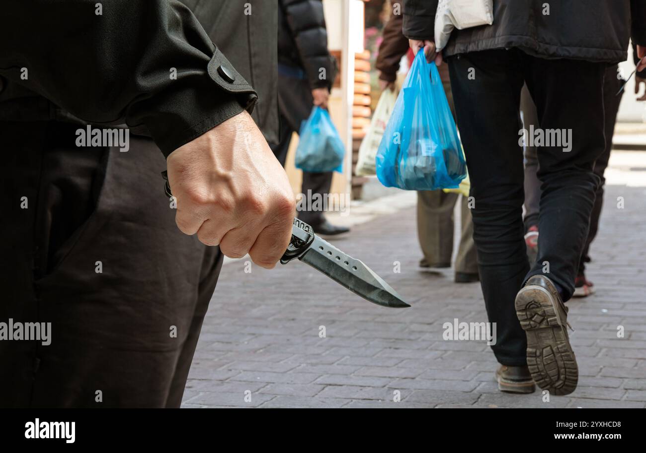 Criminal holding a knife closeup view, city street background, armed ...
