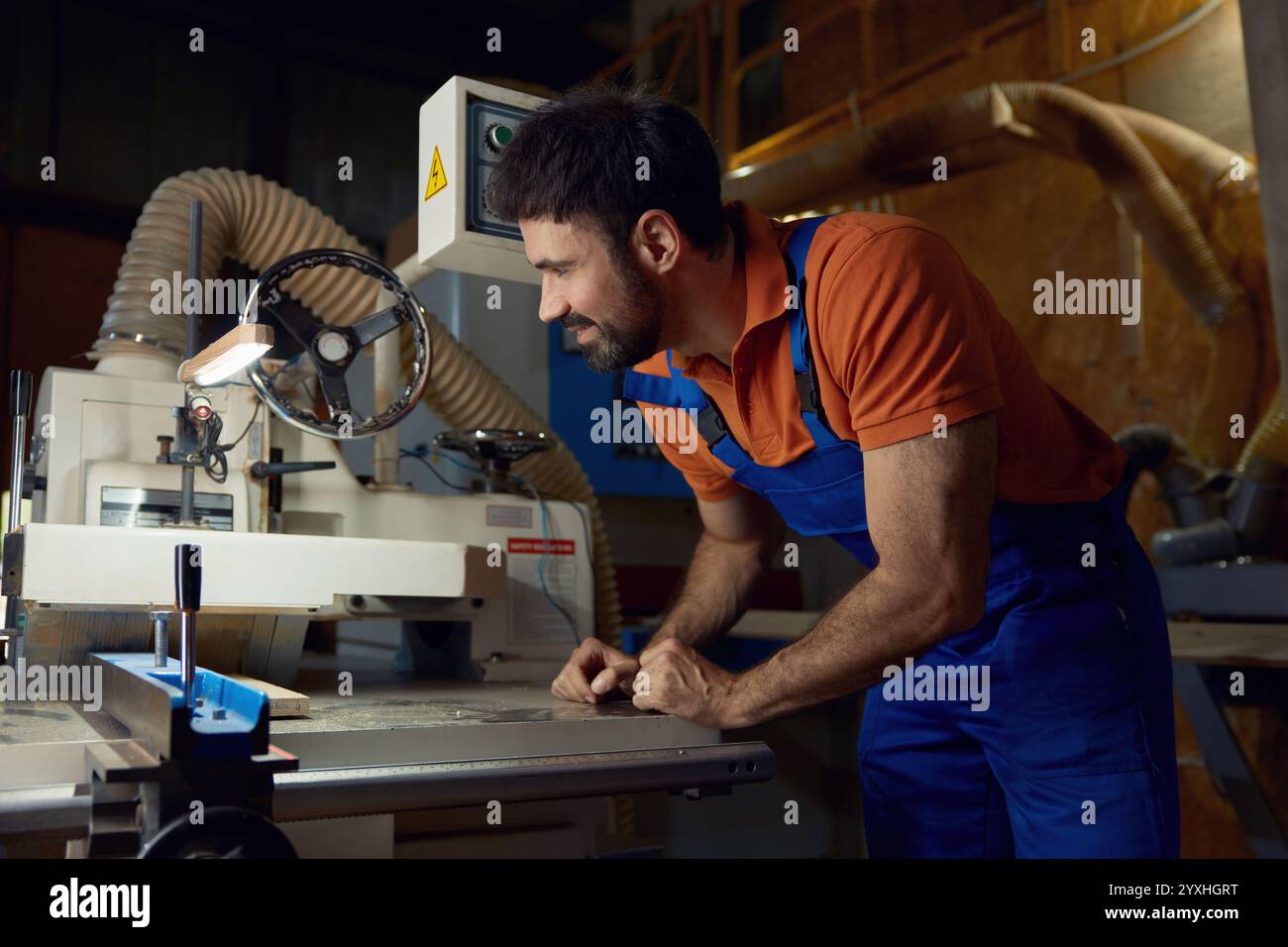 Woodworker using planer machine for production wooden materials specific size Stock Photo