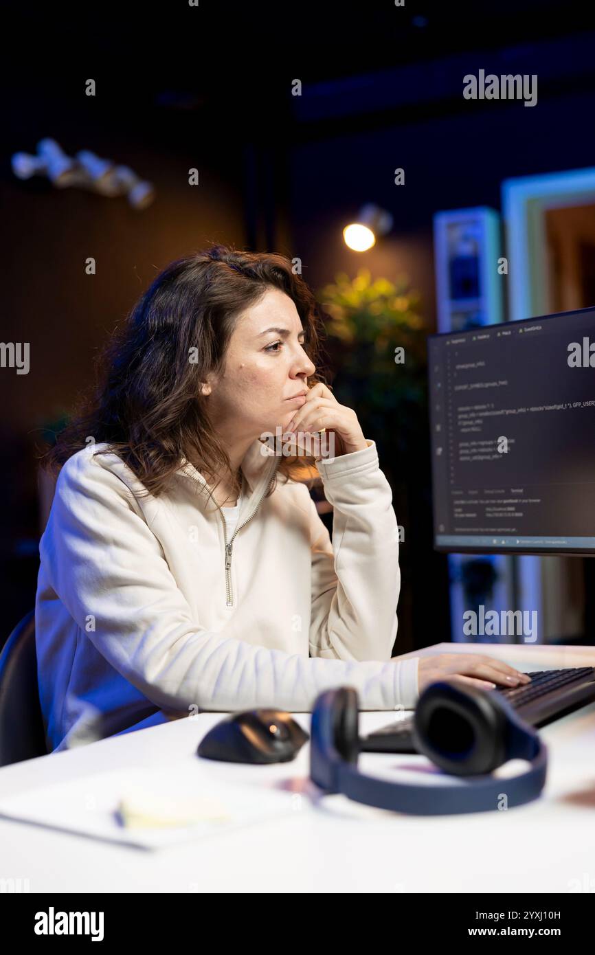 Freelancer doing software debugging using computer, checking errors in lines of code displayed on PC monitors. IT professional in apartment fixing coding issues using desktop PC Stock Photo