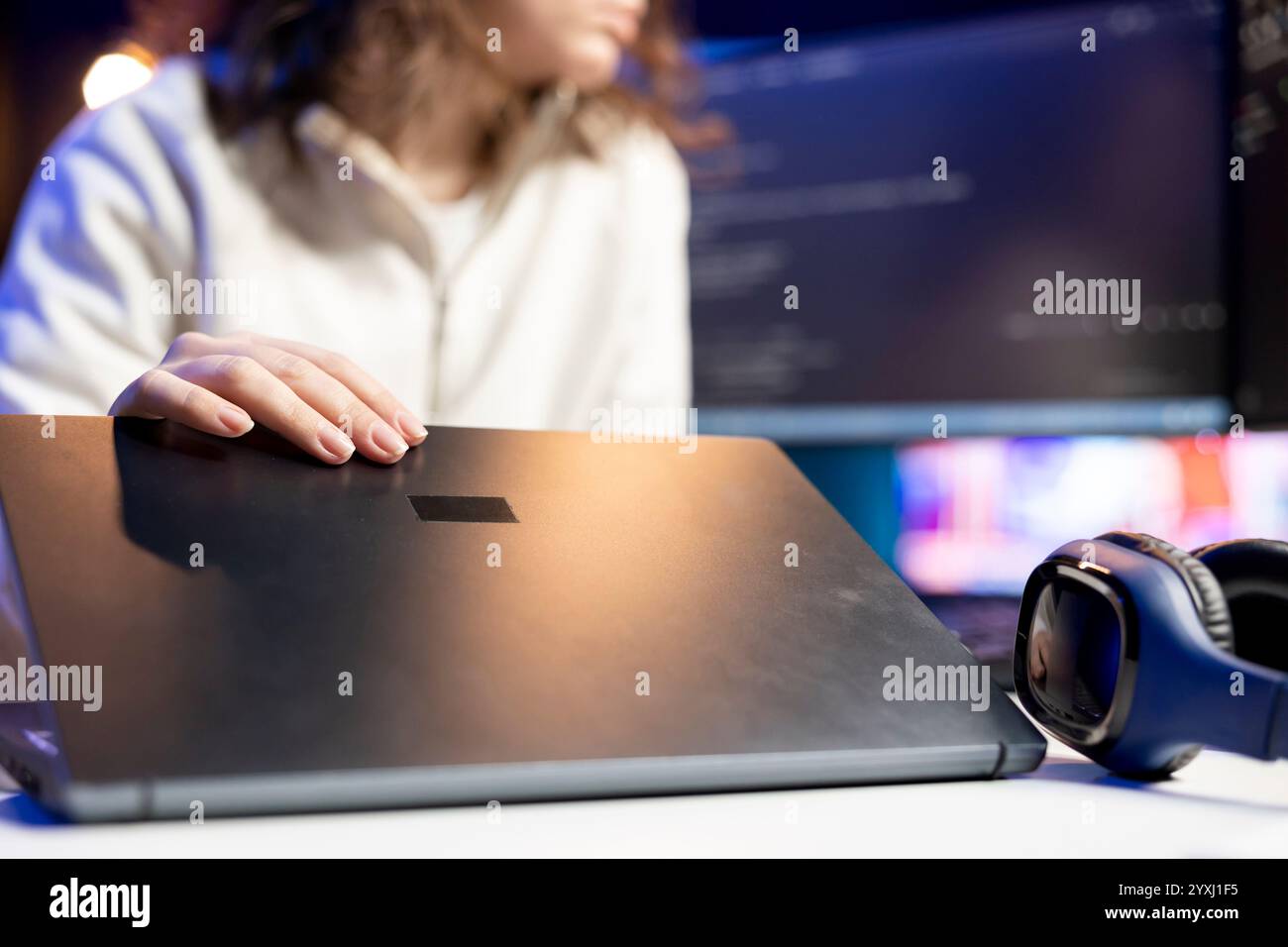 Technician doing software debugging using laptop, checking errors in lines of code displayed on computer monitors. Woman working from home fixing coding mistakes using notebook device Stock Photo