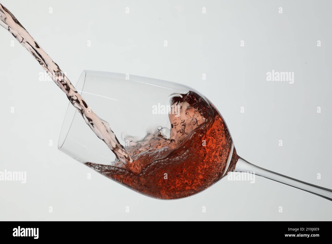 Pouring rose wine into glass on white background Stock Photo - Alamy