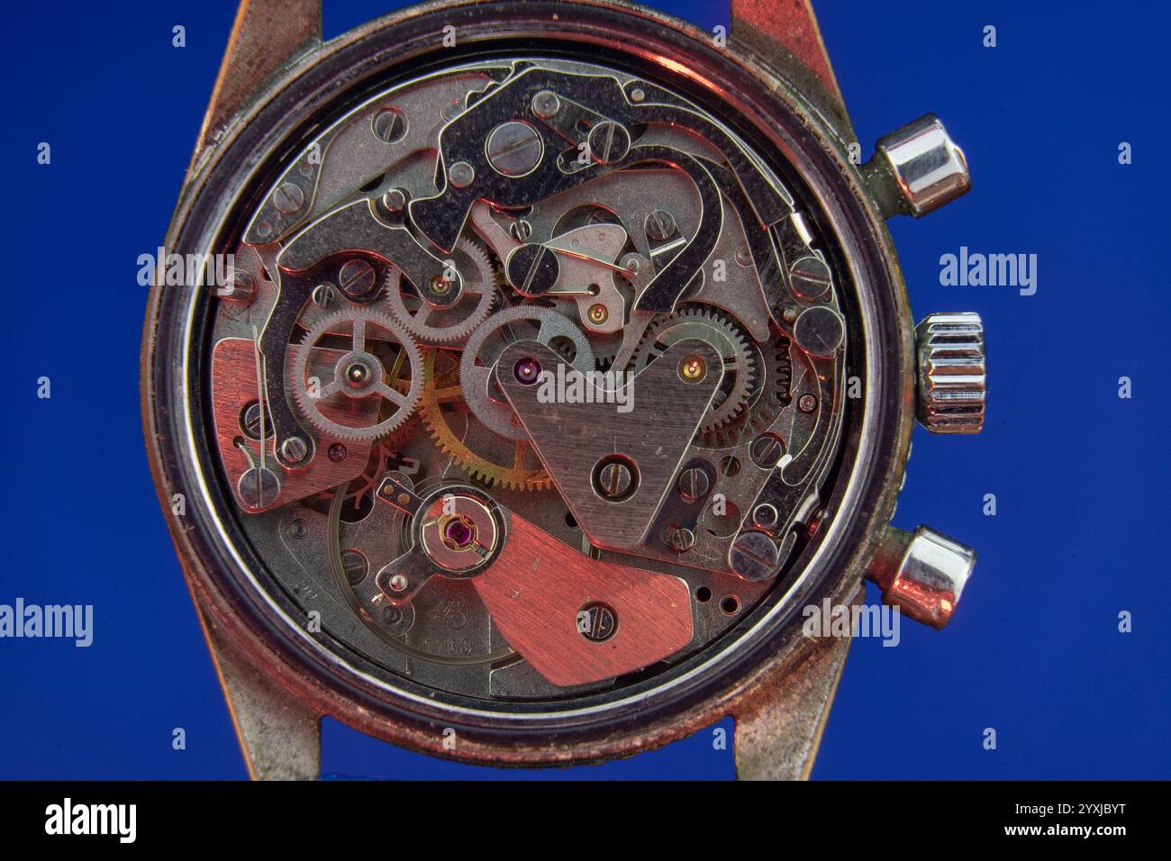 Old clock mechanism with red incident light and blue background Stock Photo