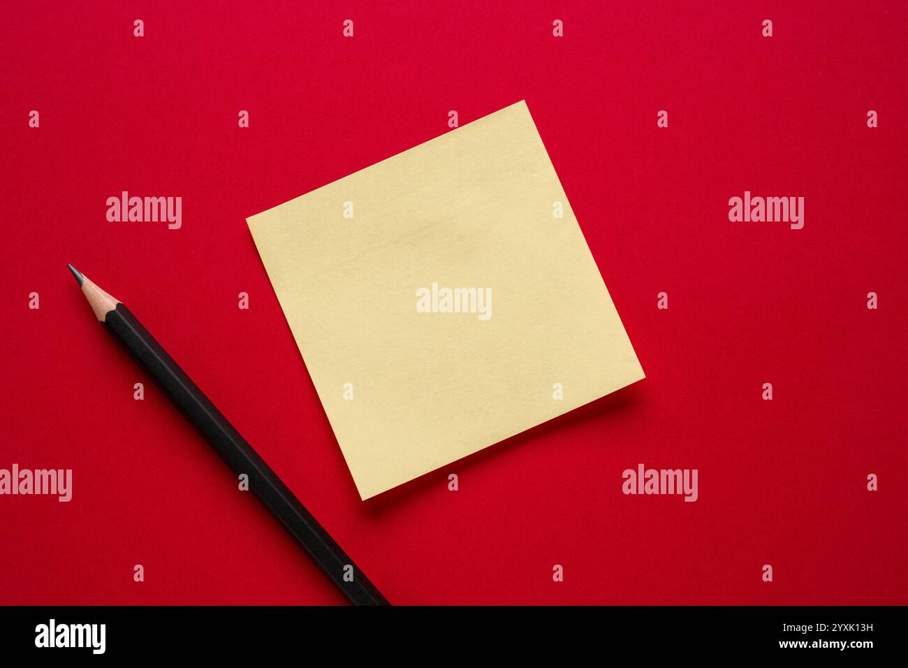Yellow blank sticky note and pencil on red background Stock Photo