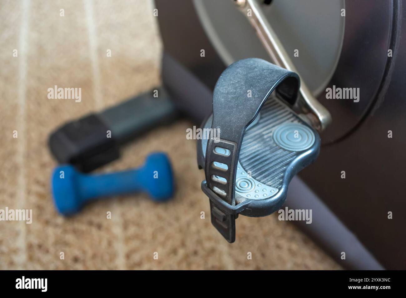 Los Angeles, California, United States - 03-25-2019: A closeup view of a stationary bike pedal and a blue dumb bell. Stock Photo