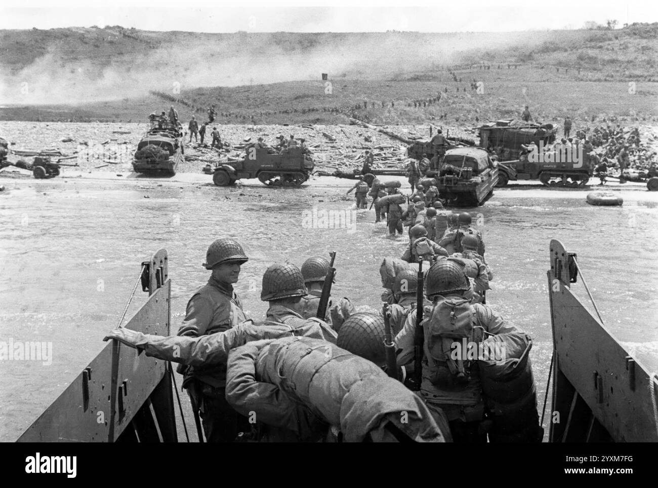 Troops wade ashore at Omaha Beach from a LCVP landing craft. Note DUKWs ...