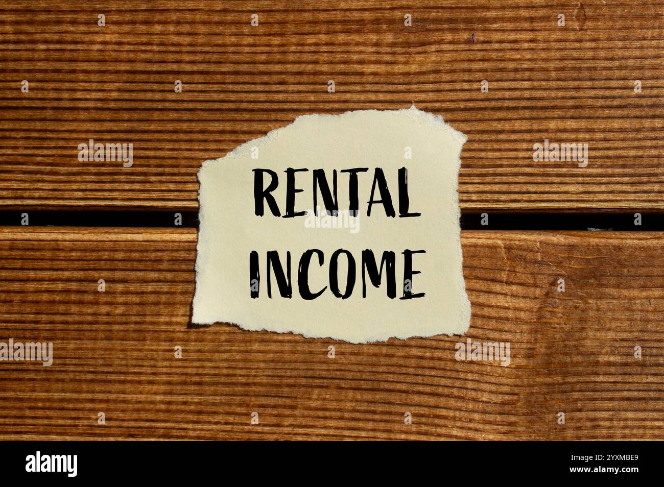 Rental income message written on ripped torn paper with wooden ...