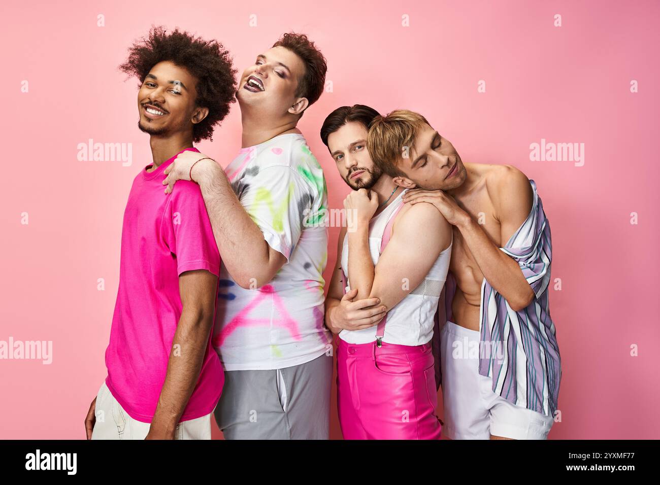 Four individuals express joy and pride in their vibrant outfits against a bright pink background. Stock Photo