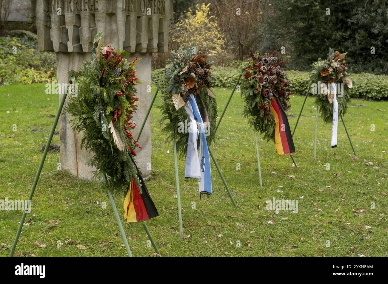 Funeral wreaths with german flags and ribbons are placed on stands in front of a war memorial Stock Photo