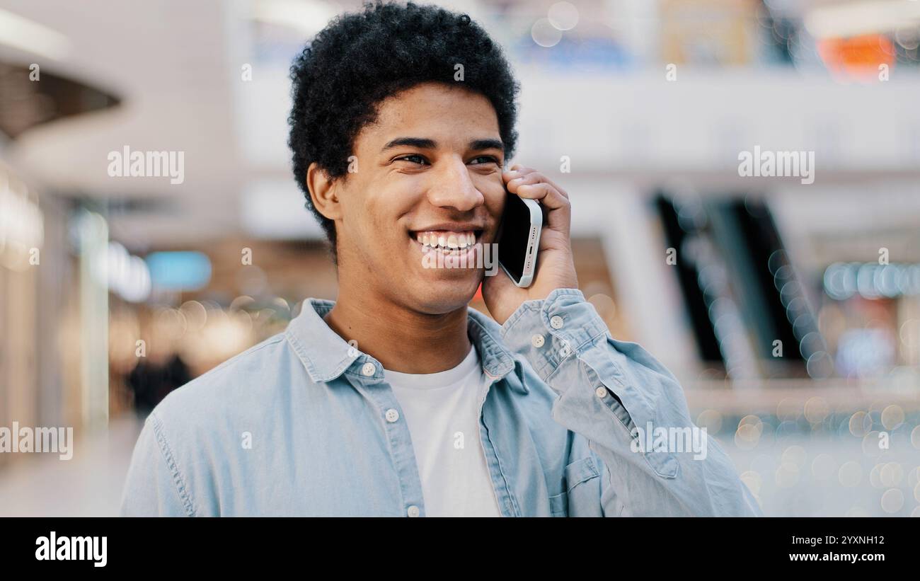 Close-up african guy looking at mobile phone answering unexpected call talking to girlfriend family smiling laughing chatting on cellphone remote Stock Photo