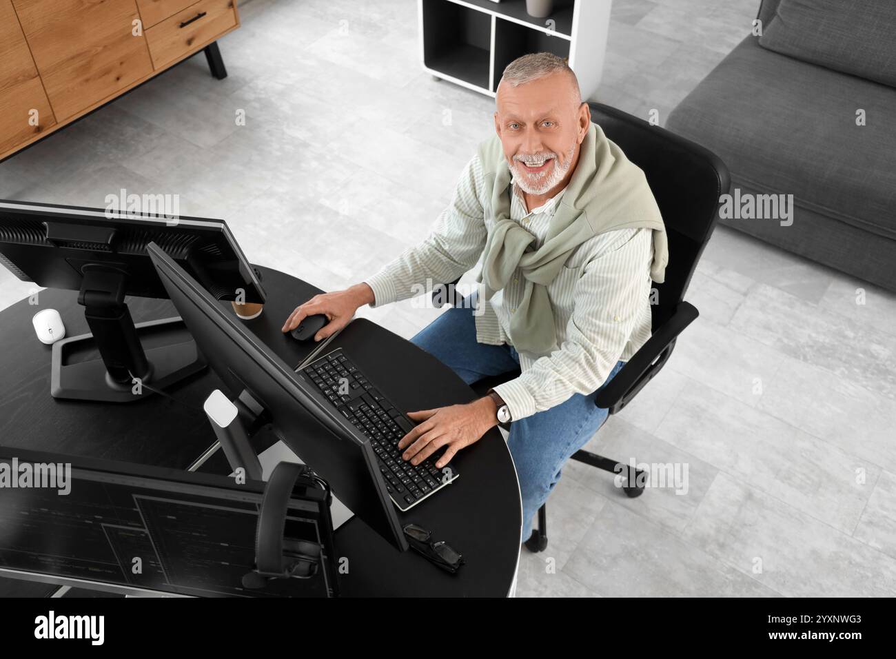 Mature programmer working with computer at table in office, top view Stock Photo