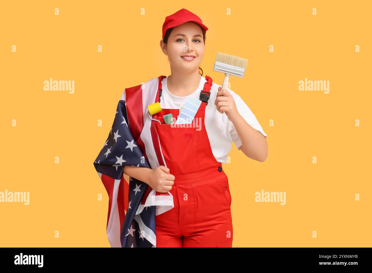 Young female painter with USA flag and brush on orange background Stock Photo