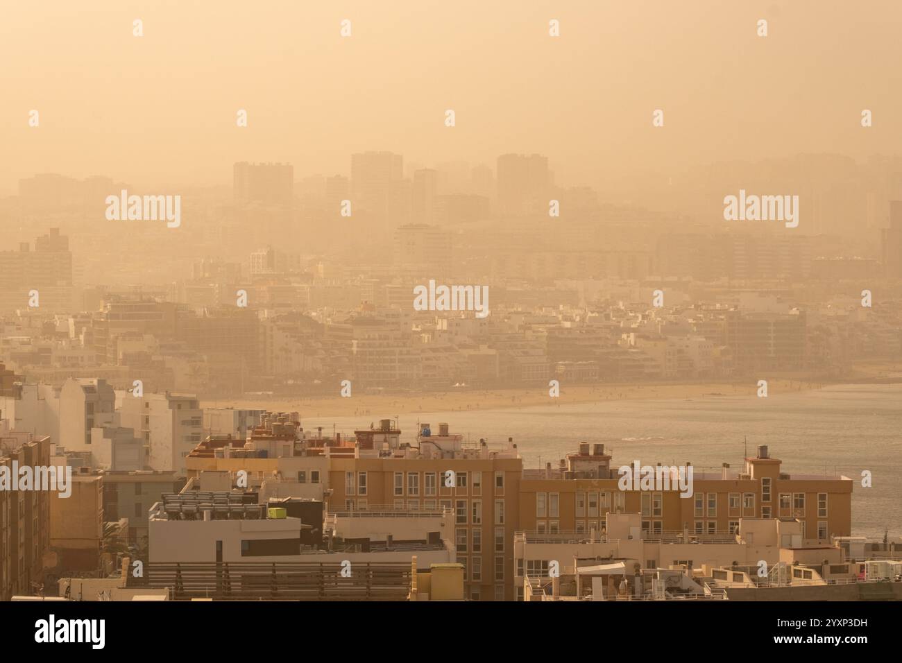 Las Palmas, Gran Canaria, Canary Islands, Spain. 17th December, 2024. Hot and eerie on the city beach in Las Palmas on Gran Canaria as hot and dusty Saharan winds (Calima) reduce visibility and air quality in the Canary Islands. PICTURED: view over Las Palmas city and city beach. Credit: Alan Dawson/Alamy Live News. Stock Photo