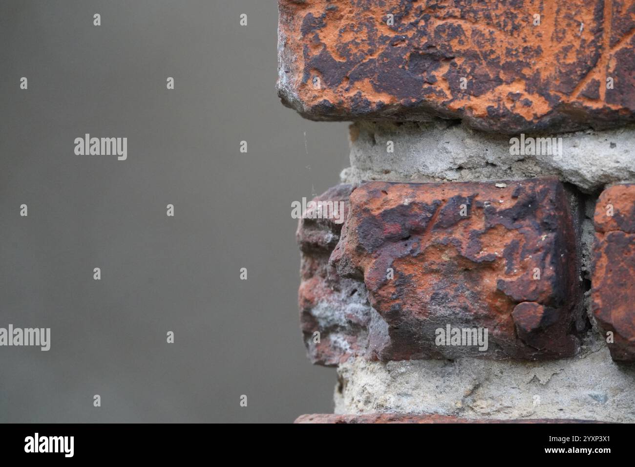 A brick wall with a brick on the corner. The brick is brown and has a rough texture Stock Photo