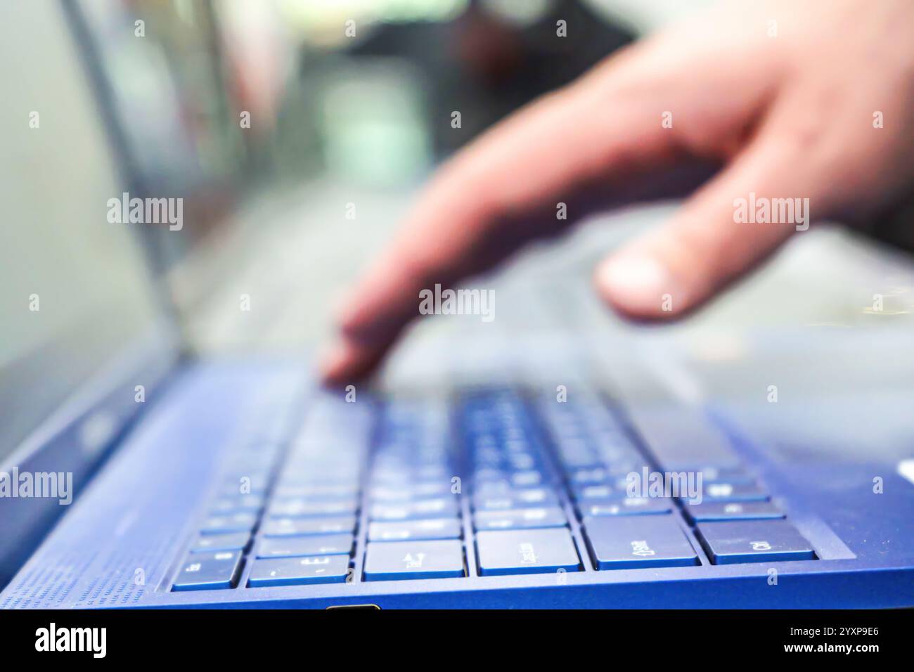 Hand typing on a blue laptop keyboard Stock Photo - Alamy